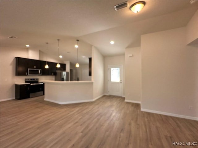 kitchen featuring lofted ceiling, decorative light fixtures, a kitchen island, stainless steel appliances, and hardwood / wood-style floors