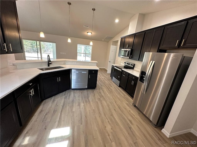 kitchen with lofted ceiling, sink, appliances with stainless steel finishes, light hardwood / wood-style floors, and decorative light fixtures