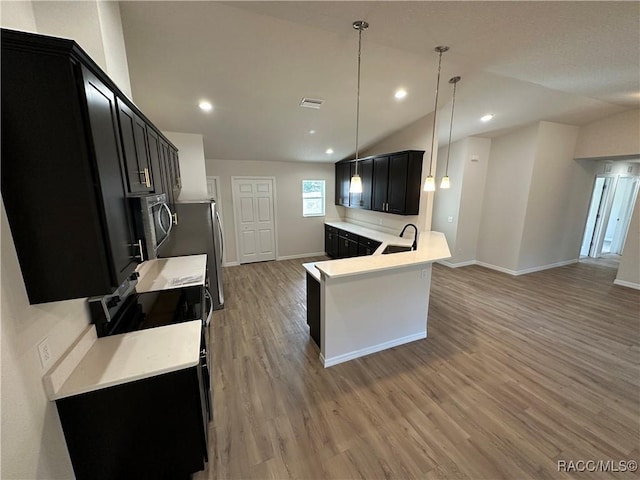 kitchen with sink, hardwood / wood-style flooring, stainless steel appliances, decorative light fixtures, and vaulted ceiling