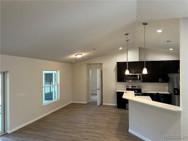 kitchen with vaulted ceiling, pendant lighting, dark hardwood / wood-style flooring, kitchen peninsula, and stainless steel appliances