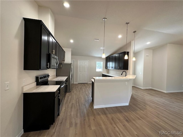 kitchen featuring lofted ceiling, sink, appliances with stainless steel finishes, hanging light fixtures, and light wood-type flooring