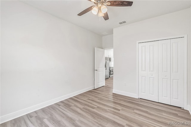 unfurnished bedroom featuring ceiling fan, stainless steel fridge, light hardwood / wood-style floors, and a closet