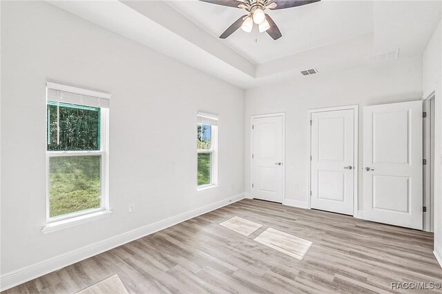 44 W Lynnhaven Pl, Citrus Springs, FL 34434 - unfurnished bedroom featuring light wood-style floors, baseboards, a ceiling fan, and a raised ceiling