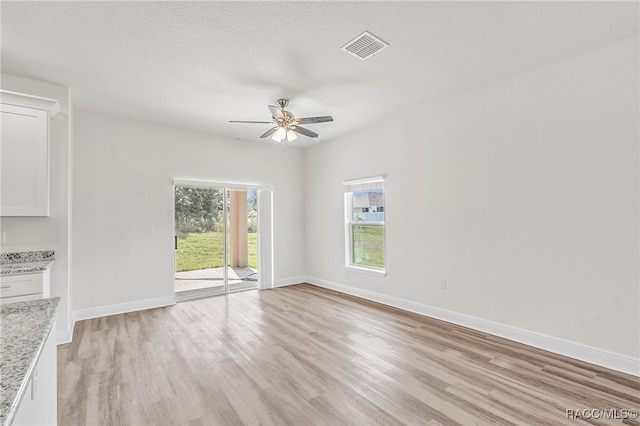 empty room featuring ceiling fan, light hardwood / wood-style floors, and a textured ceiling