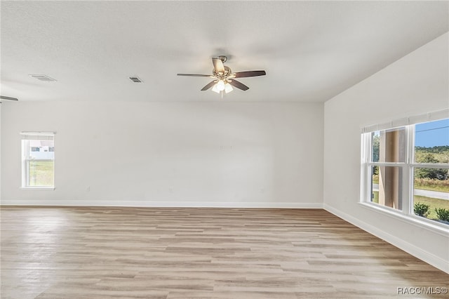 empty room featuring a textured ceiling, light wood-type flooring, and ceiling fan