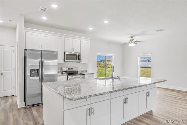 kitchen featuring a center island with sink, white cabinets, and appliances with stainless steel finishes