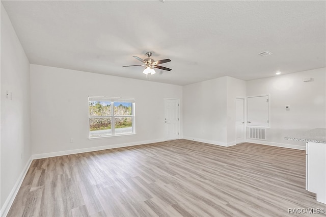 unfurnished room featuring a textured ceiling, light wood-type flooring, and ceiling fan