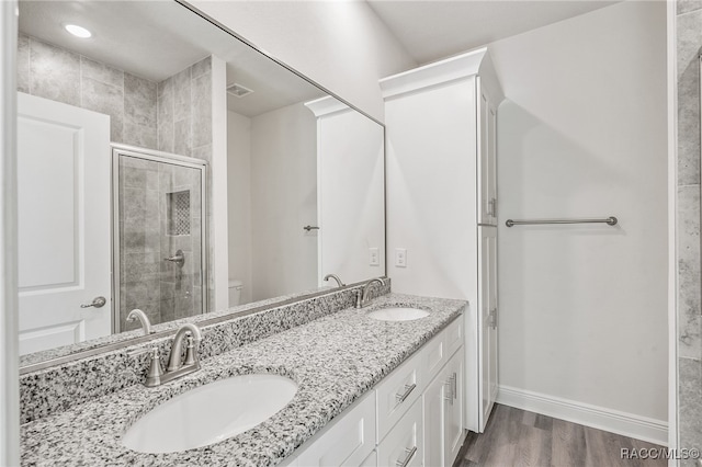 bathroom featuring toilet, vanity, a shower with shower door, and hardwood / wood-style flooring