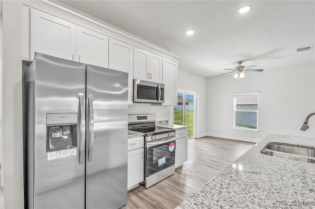 44 W Lynnhaven Pl, Citrus Springs, FL 34434 - kitchen featuring appliances with stainless steel finishes, a sink, a ceiling fan, light stone countertops, and white cabinets