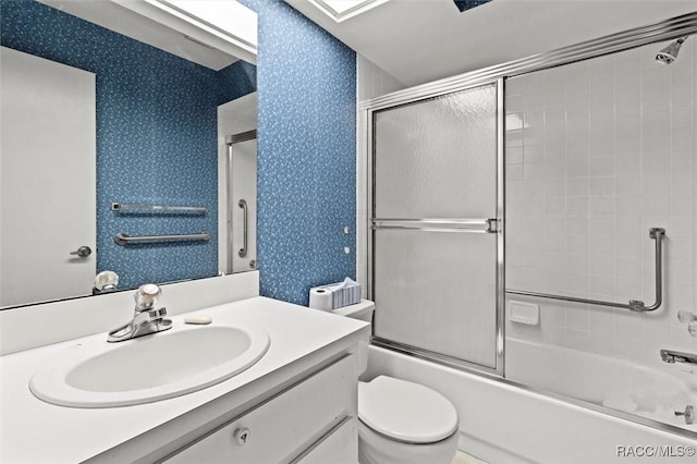 bathroom with vanity, toilet, shower / bath combination with glass door, and wallpapered walls