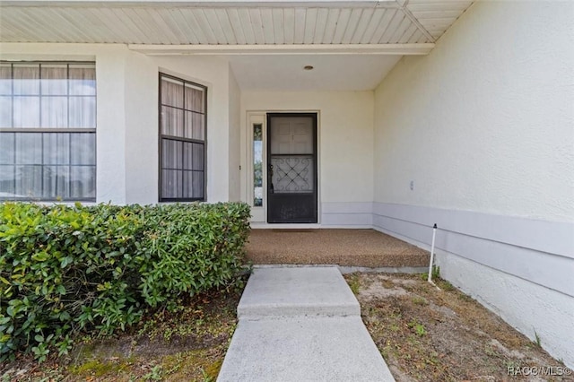 view of exterior entry featuring a porch and stucco siding
