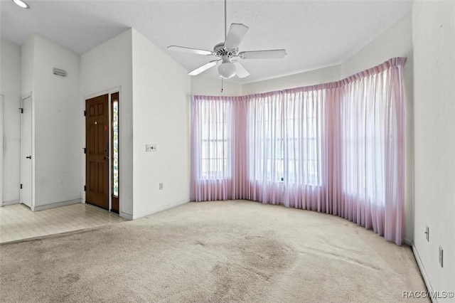 carpeted spare room with a ceiling fan and baseboards