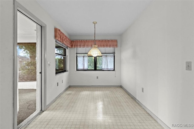 unfurnished dining area featuring light floors and baseboards