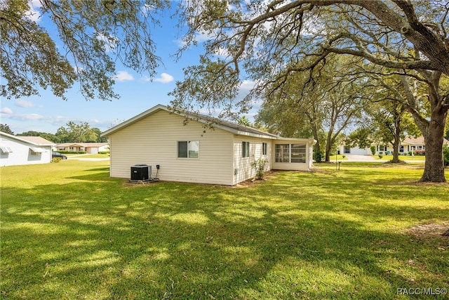 back of property featuring a lawn and cooling unit