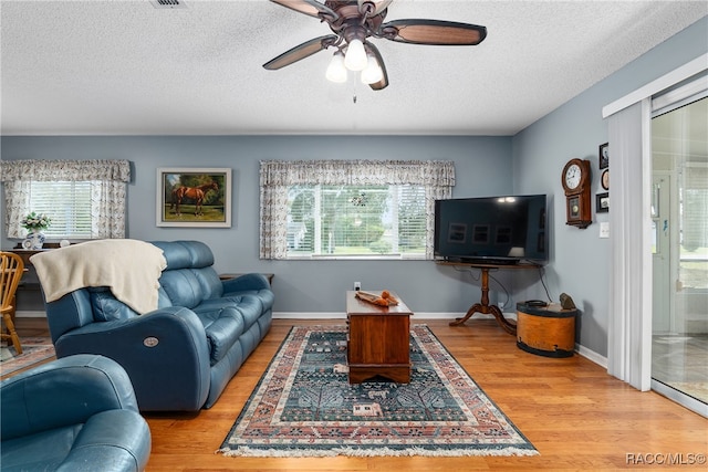 living room featuring hardwood / wood-style floors, ceiling fan, and a textured ceiling