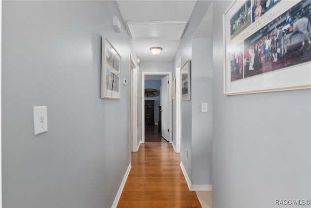 hall with hardwood / wood-style floors and a textured ceiling