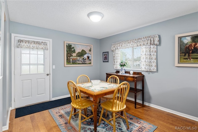 dining space featuring a textured ceiling and light hardwood / wood-style flooring