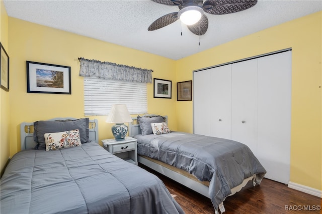 bedroom with a textured ceiling, ceiling fan, dark wood-type flooring, and a closet