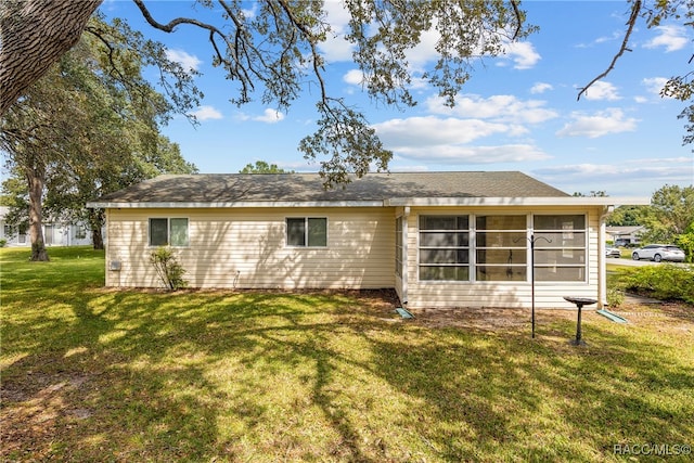 rear view of house featuring a lawn and a sunroom