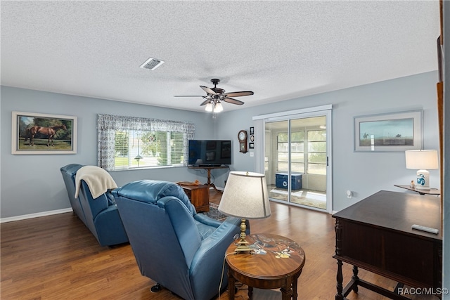 living room featuring a textured ceiling, ceiling fan, a healthy amount of sunlight, and dark hardwood / wood-style floors