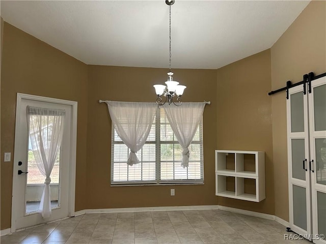 unfurnished dining area featuring a barn door and a chandelier