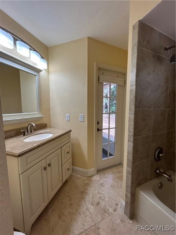 bathroom with vanity, a textured ceiling, and tiled shower / bath