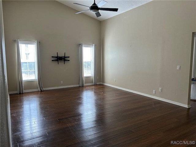 empty room with ceiling fan, dark hardwood / wood-style flooring, and high vaulted ceiling