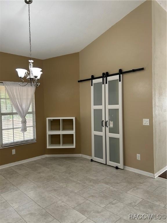 spare room with a barn door and a chandelier