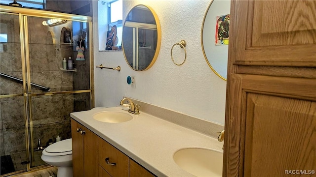 bathroom with vanity, toilet, and a shower with door