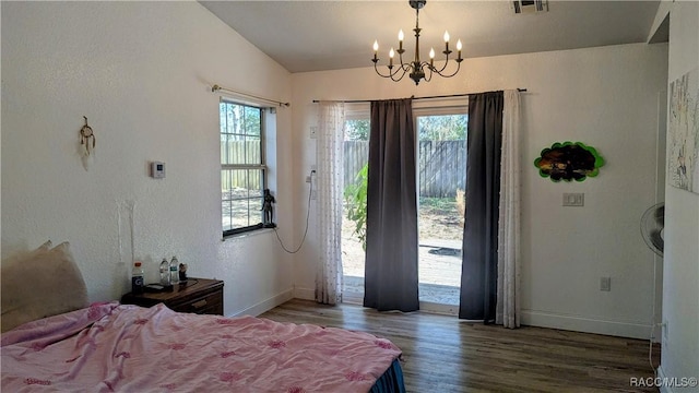 bedroom with hardwood / wood-style flooring, an inviting chandelier, vaulted ceiling, and access to outside