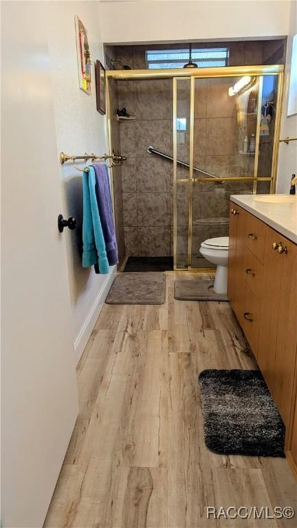 bathroom featuring vanity, wood-type flooring, a shower with door, and toilet