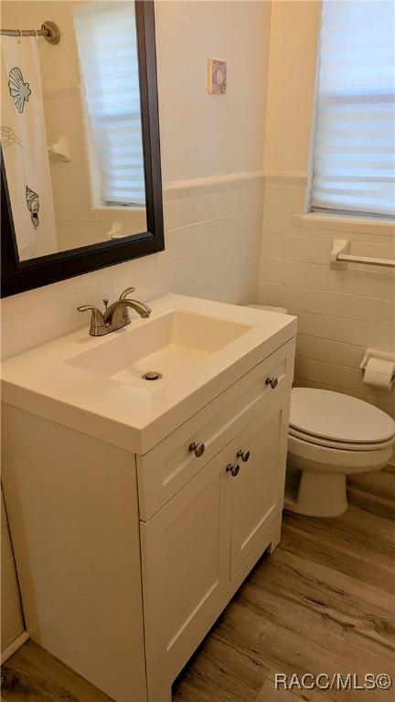 bathroom featuring vanity, hardwood / wood-style flooring, tile walls, and toilet