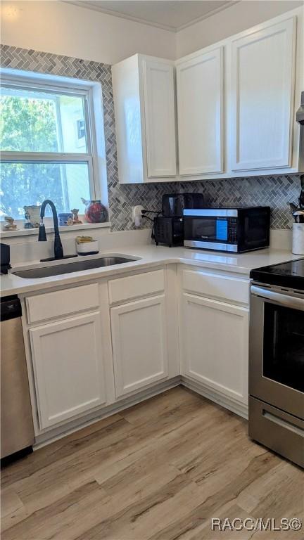 kitchen with white cabinetry, appliances with stainless steel finishes, light hardwood / wood-style floors, and sink