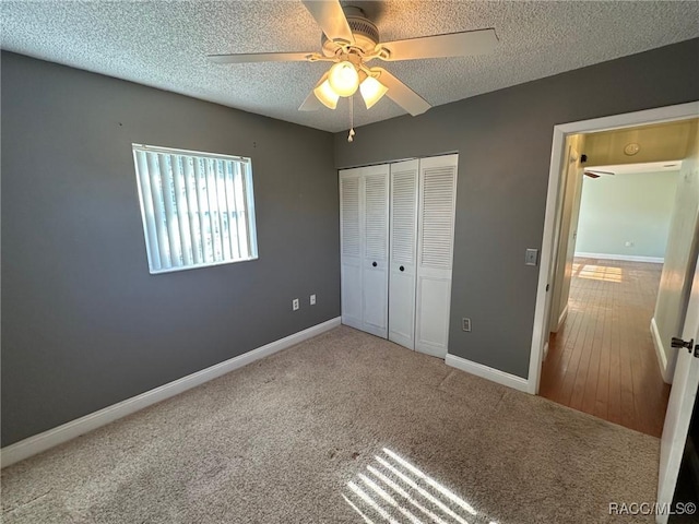 unfurnished bedroom featuring ceiling fan, carpet floors, a closet, and a textured ceiling