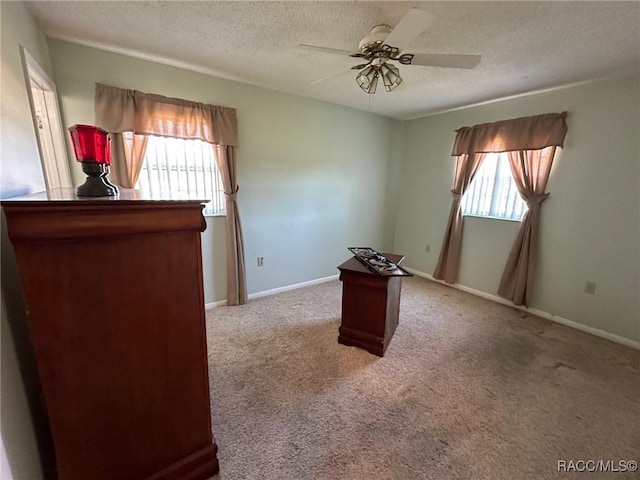 interior space featuring light colored carpet, a textured ceiling, and ceiling fan