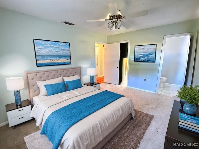 bedroom with ceiling fan, ensuite bathroom, and carpet flooring