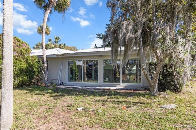 rear view of property with a yard and metal roof