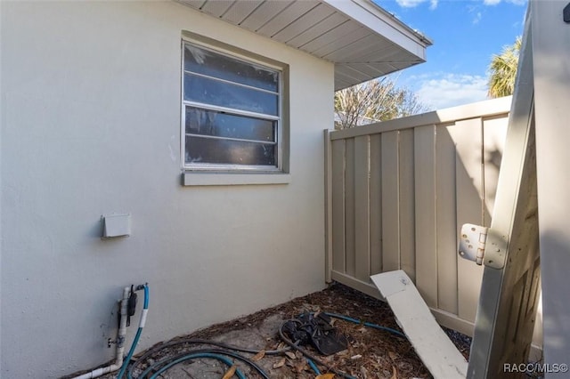 view of property exterior with stucco siding and fence