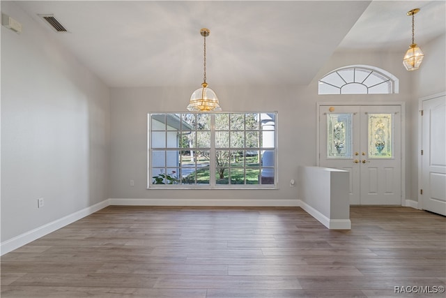 entryway featuring hardwood / wood-style floors, a notable chandelier, vaulted ceiling, and french doors