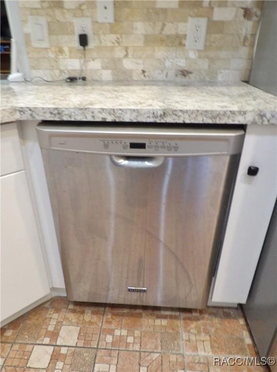 interior details with white cabinetry, stainless steel dishwasher, and backsplash