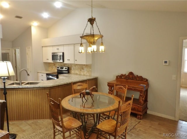 kitchen featuring vaulted ceiling, sink, white cabinets, decorative backsplash, and stainless steel appliances