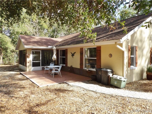 rear view of house featuring a sunroom and a patio