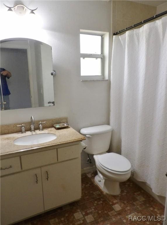 bathroom featuring vanity, toilet, and curtained shower