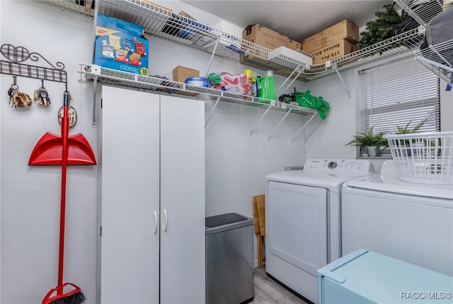 laundry room with washing machine and dryer and light hardwood / wood-style floors