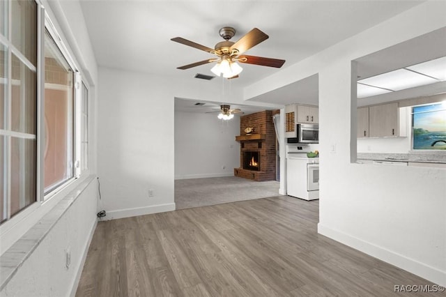 3874 N Timucua Pt, Crystal River, FL 34428 - unfurnished living room with a ceiling fan, a brick fireplace, and light wood-style flooring