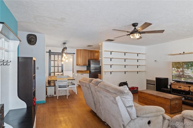 208 S Adams St, Beverly Hills, FL 34465 - living area with light wood-style flooring, a barn door, ceiling fan, and a textured ceiling