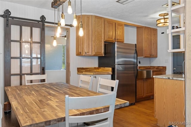 208 S Adams St, Beverly Hills, FL 34465 - kitchen featuring freestanding refrigerator, light wood finished floors, a barn door, and brown cabinets