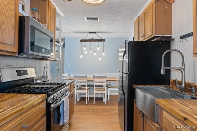 208 S Adams St, Beverly Hills, FL 34465 - kitchen with appliances with stainless steel finishes, wooden counters, light wood-style flooring, and brown cabinets