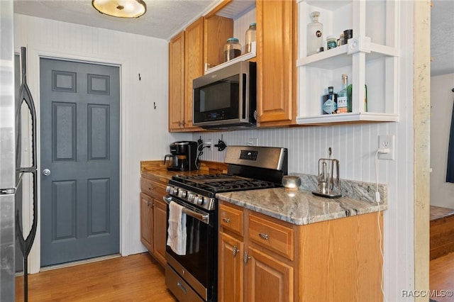 208 S Adams St, Beverly Hills, FL 34465 - kitchen featuring stainless steel appliances, open shelves, light wood-style flooring, light stone counters, and brown cabinetry