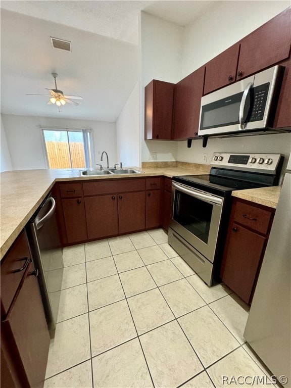 kitchen with sink, ceiling fan, light tile patterned floors, appliances with stainless steel finishes, and kitchen peninsula